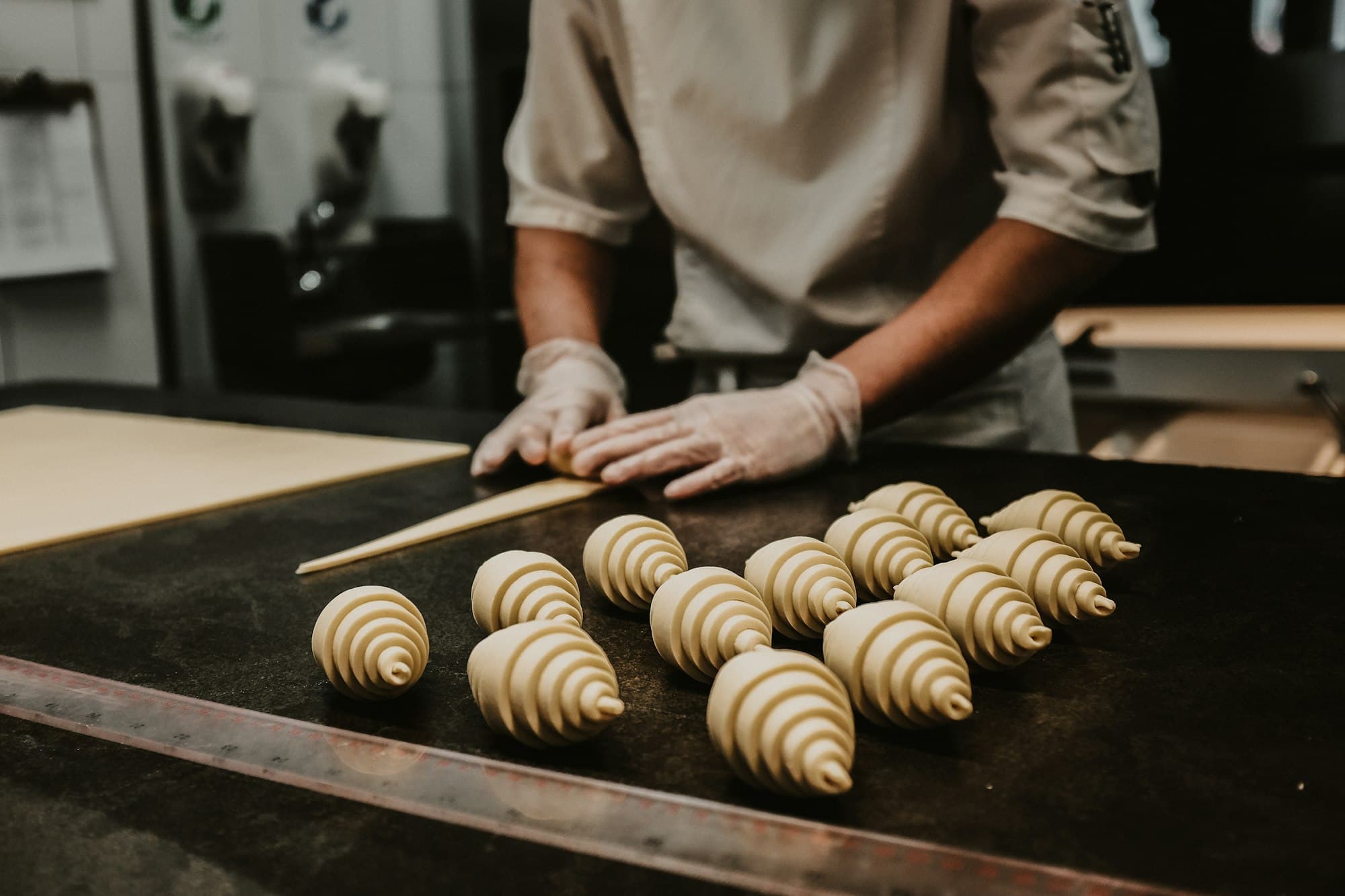 Mani che arrotolano i cornetti sul banco della pasticceria